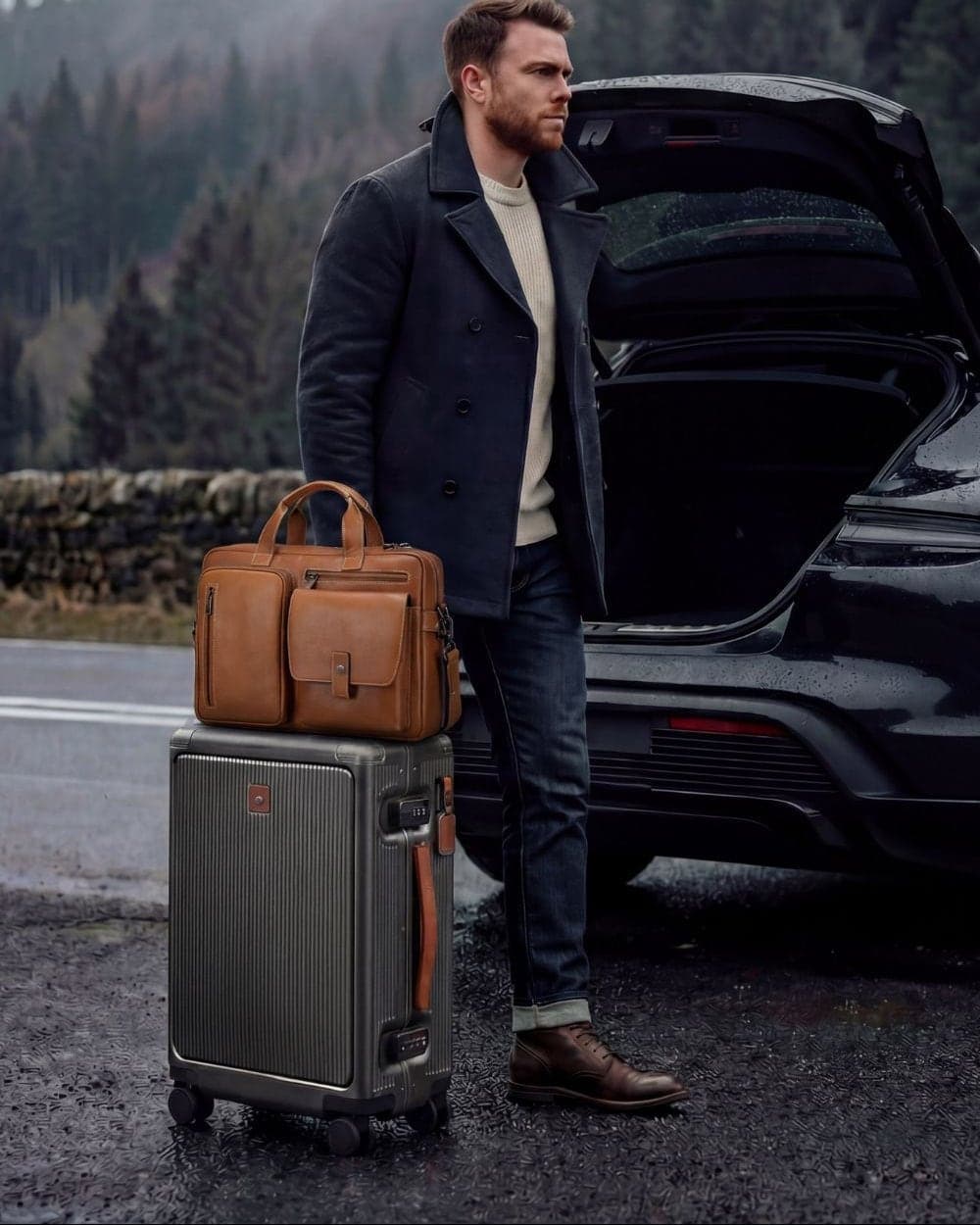 A tan briefcase and a cabin case at the back of a car on a wet mountain road